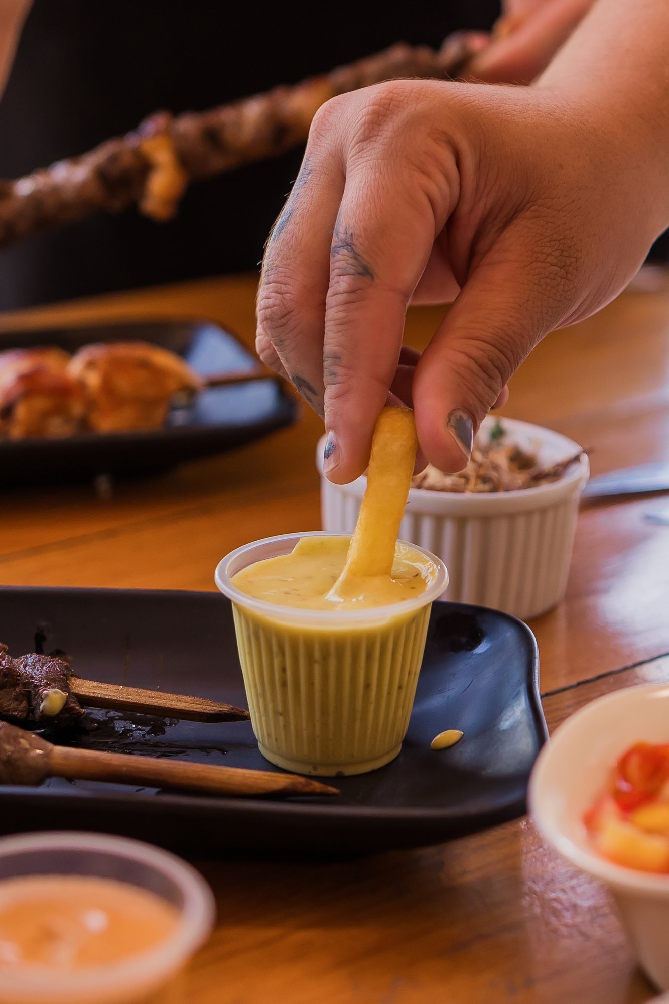 Batata frita mergulhada em molho da casa