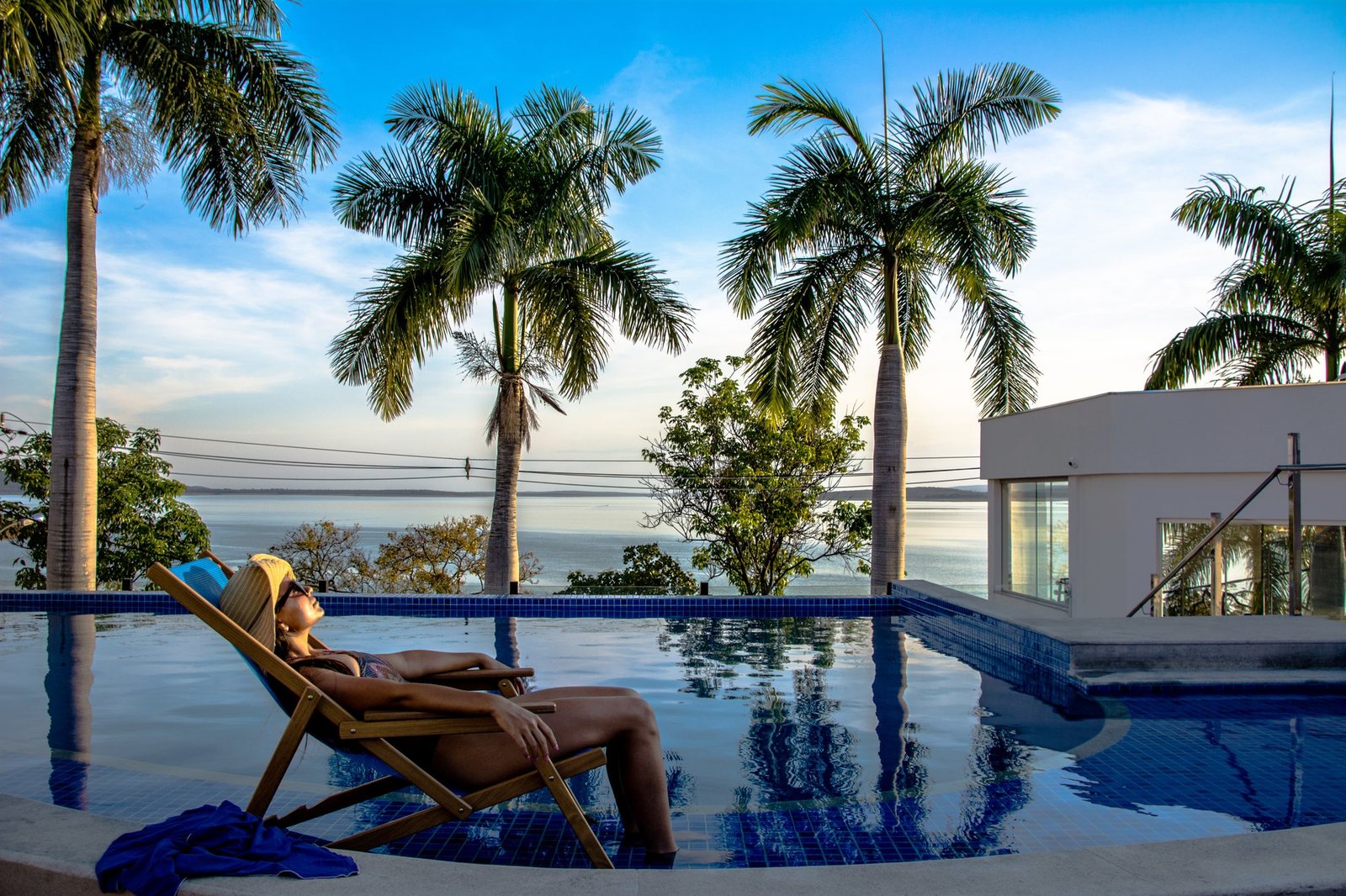 Mulher relaxando em poltrona dentro da piscina ao pôr do sol